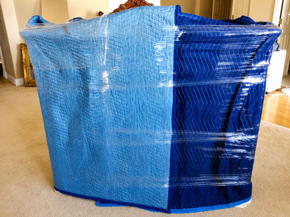 Large furniture piece shrink-wrapped and blanket-padded